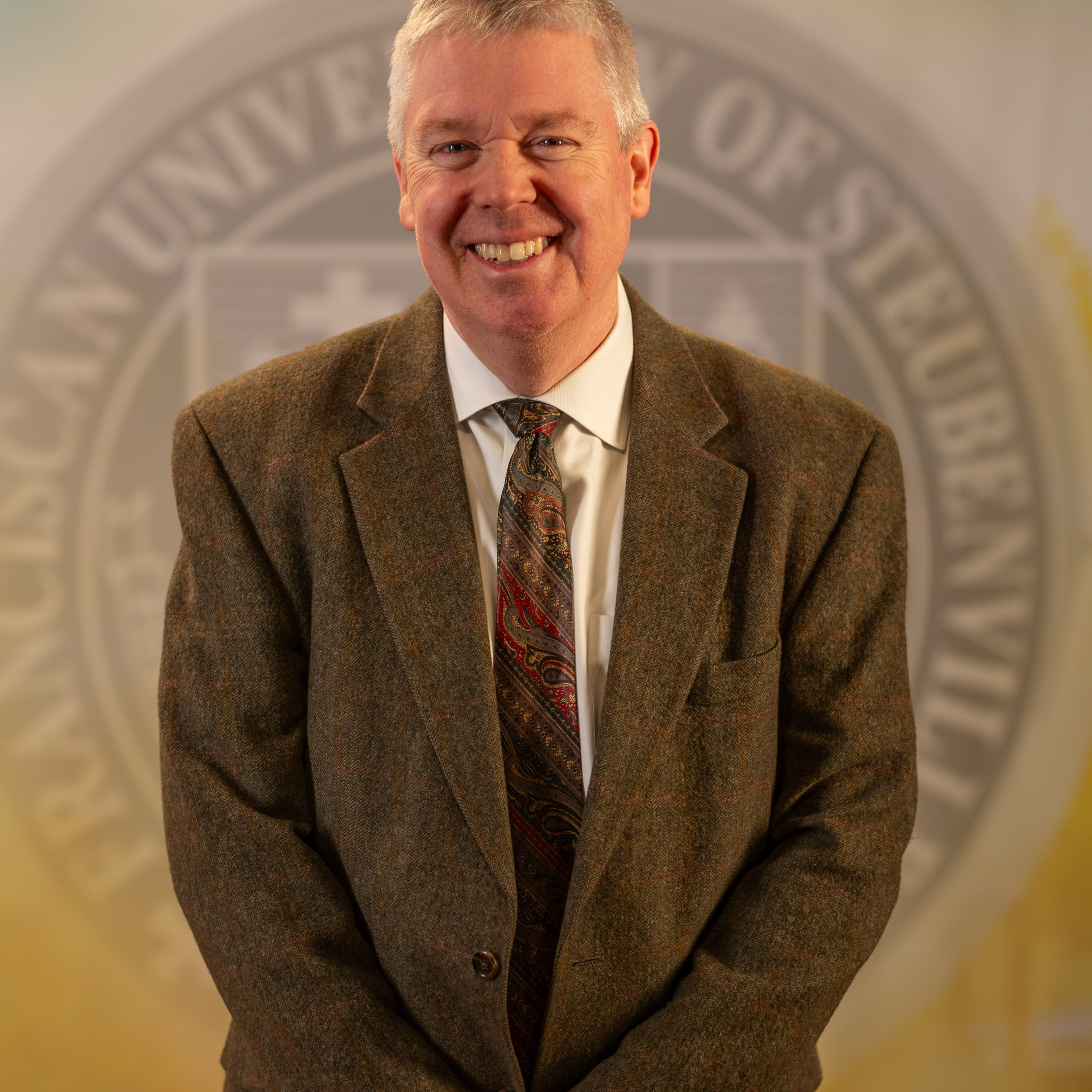 Dr. Matthew O’Brien standing in front of a university seal.