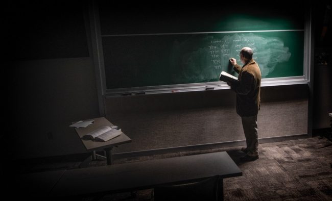 Professor writing on a chalkboard